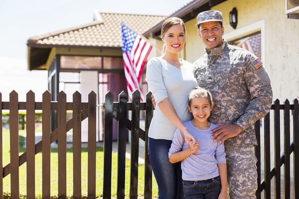 Military service member with family in front of their home purchased with a VA loan